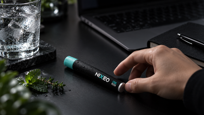 NIXEO Botanical Diffuser, COOL RUSH — lifestyle photograph on a modern desk beside a laptop and glass of ice water